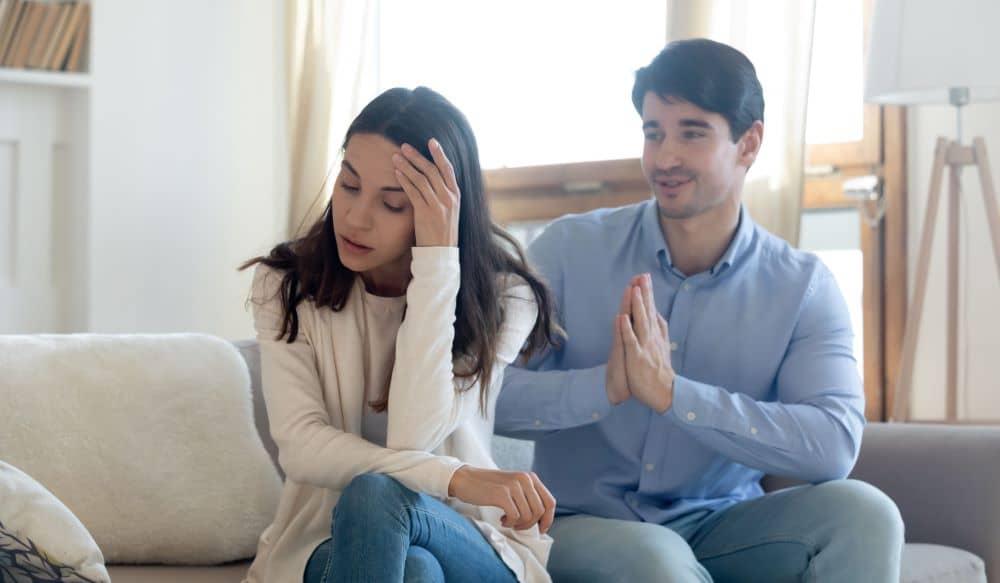 Woman ignoring a man who is asking for forgiveness.