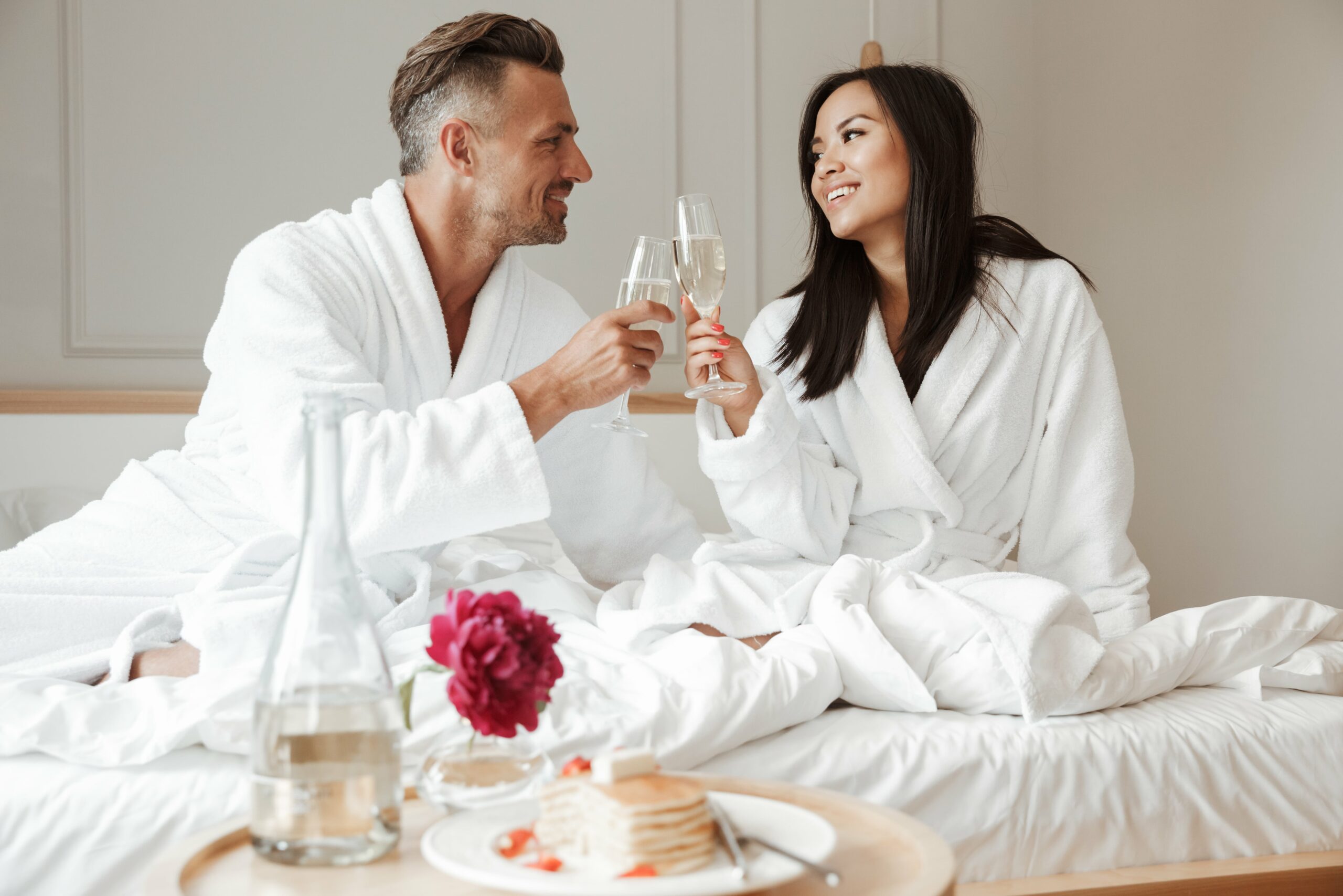 couple enjoying breakfast in bed with a glass of champagne 