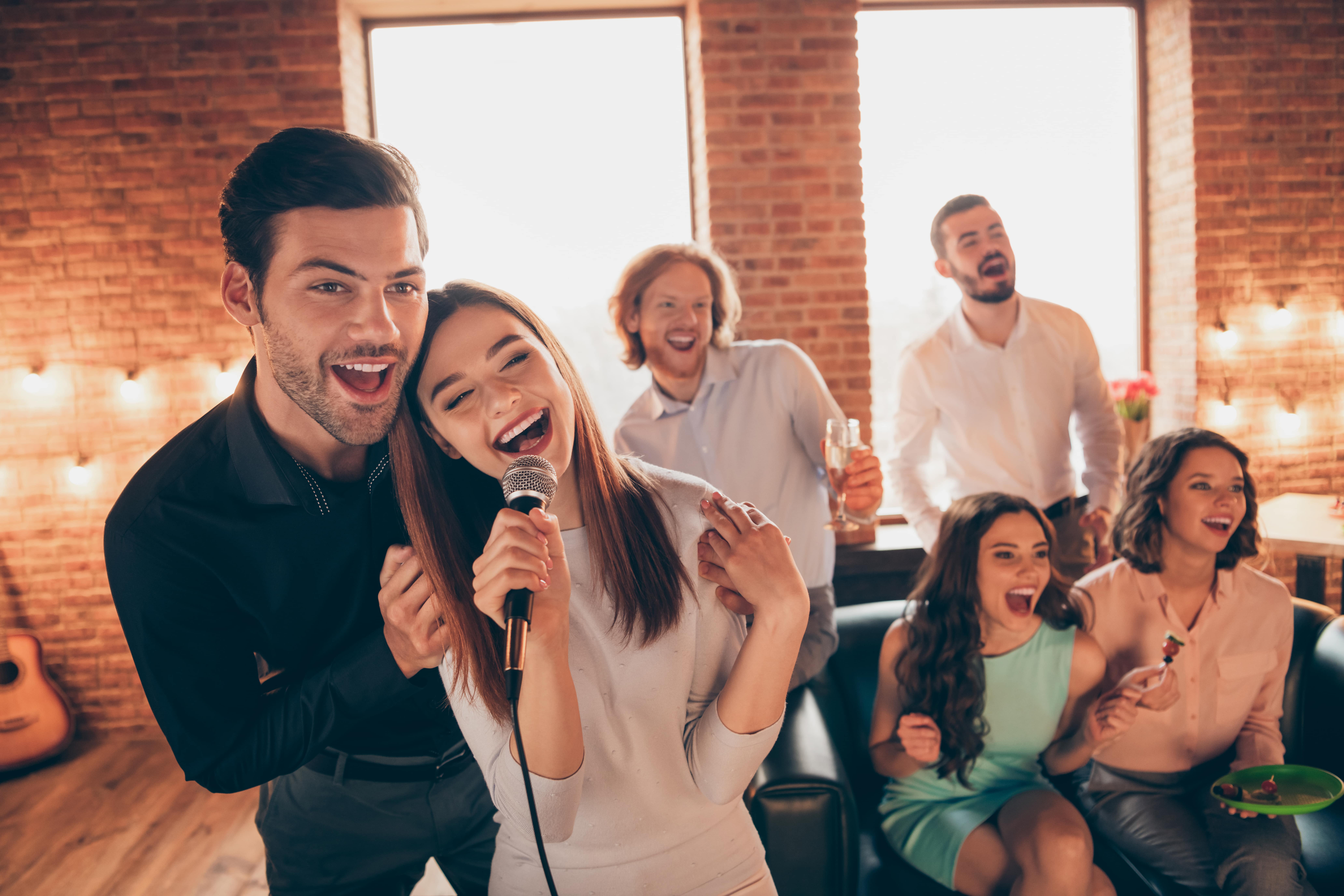 couple singing karaoke with their friends