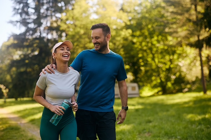 Cheerful couple having fun while exercising in nature. Copy space.