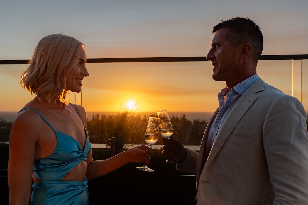 professional woman and man on a date watching sunset with champagne