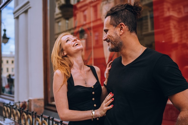 Young redhead australian woman laughing touching boyfriend outdoors. Handsome Hispanic man dating with girl.