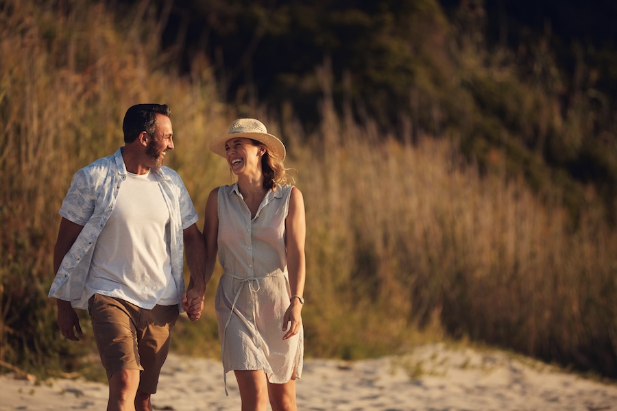 Holding hands, laugh and couple outdoor with bonding on vacation, getaway or weekend trip. Happy, walking and mature man with woman in nature for connection, care and love in marriage on holiday.